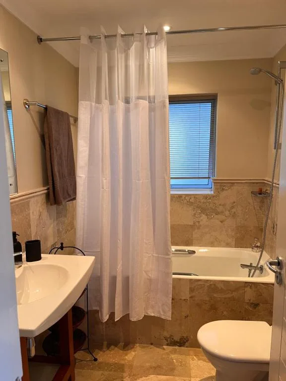Modern bathroom with vanity sink, bathtub, and shower enclosure behind curtain