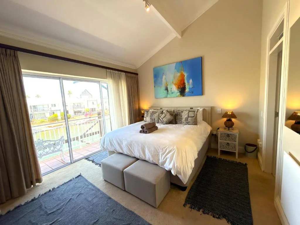 Bright bedroom with queen bed, deck access, and sailboat artwork