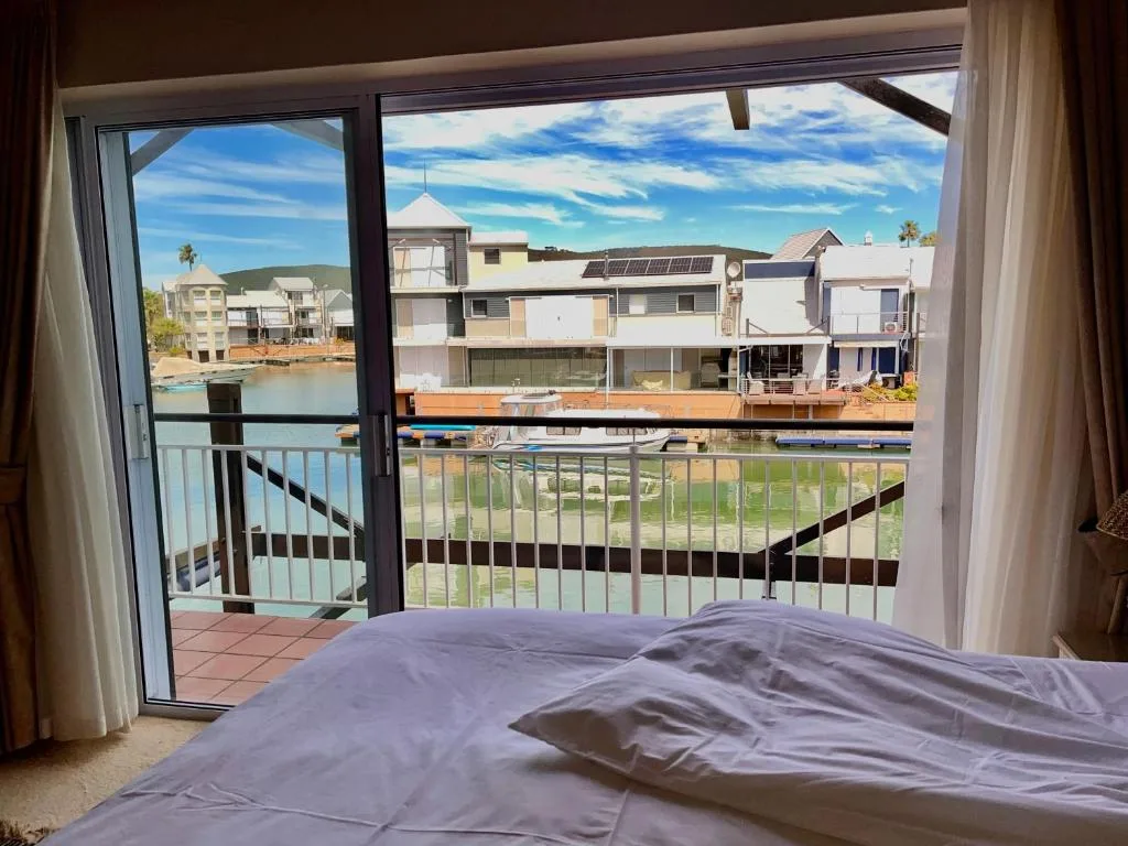 Bedroom with waterfront view through glass doors and balcony railing