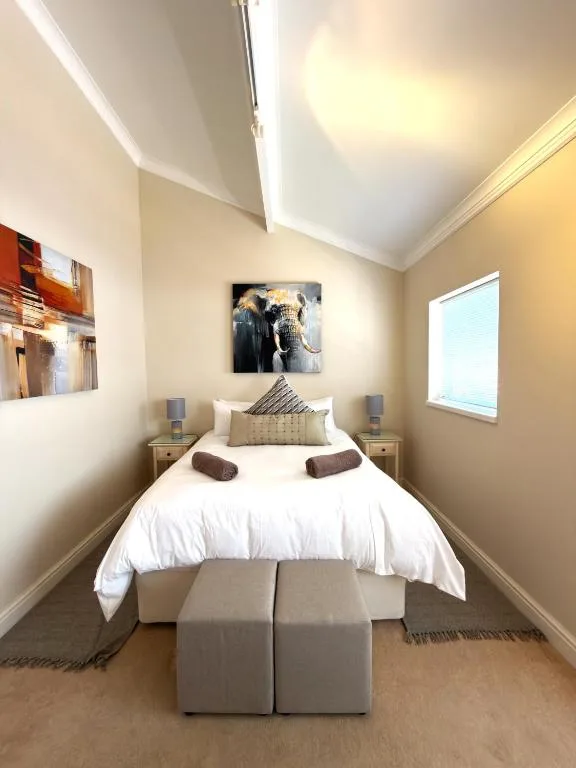 Bright modern bedroom with white bedding, side tables, and wall art