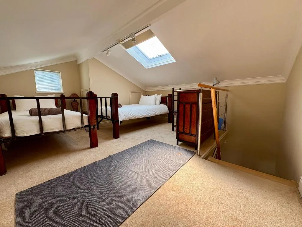Spacious attic bedroom with multiple beds and skylight window