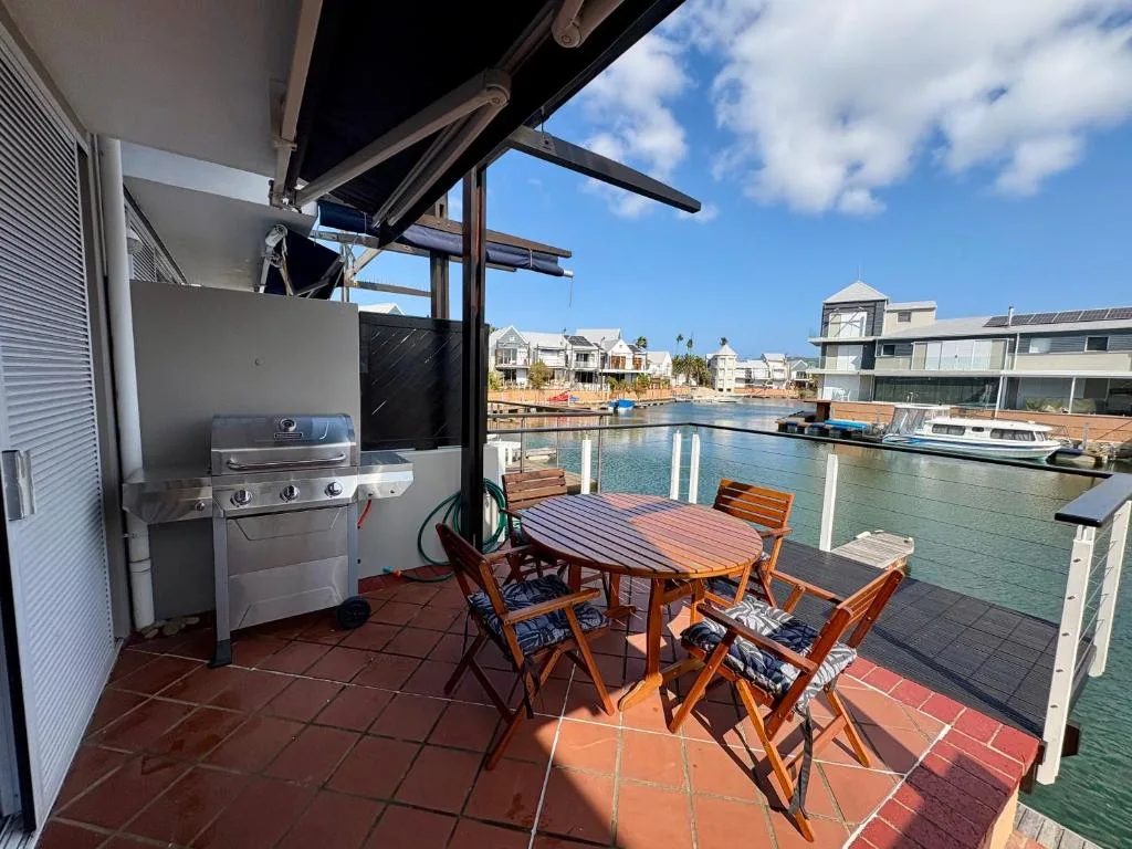 Waterfront deck with braai, dining table, and lagoon views