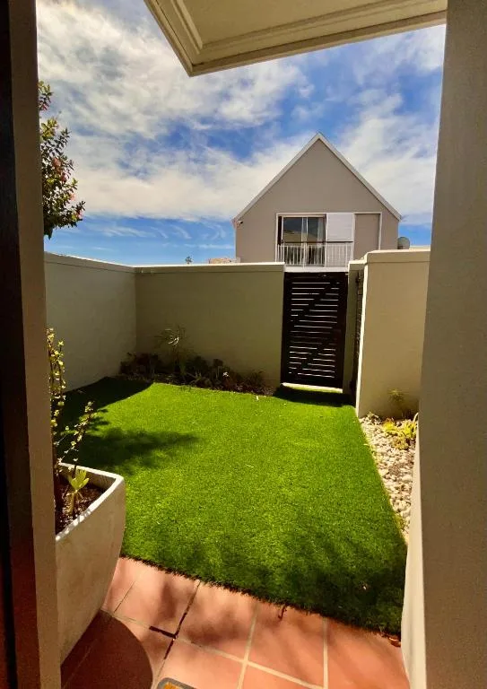 Modern courtyard with green lawn, cream walls, and mountain views beyond