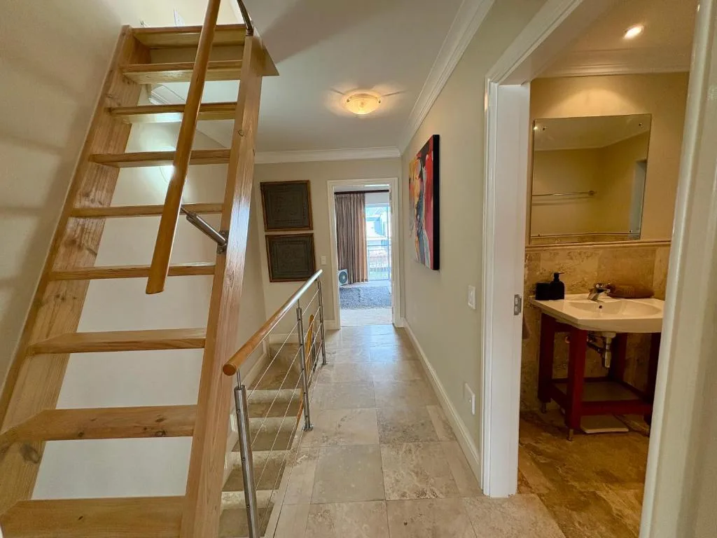 Modern hallway with wooden staircase and bathroom vanity visible