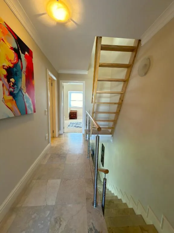 Bright hallway with wooden ladder staircase and contemporary artwork on wall