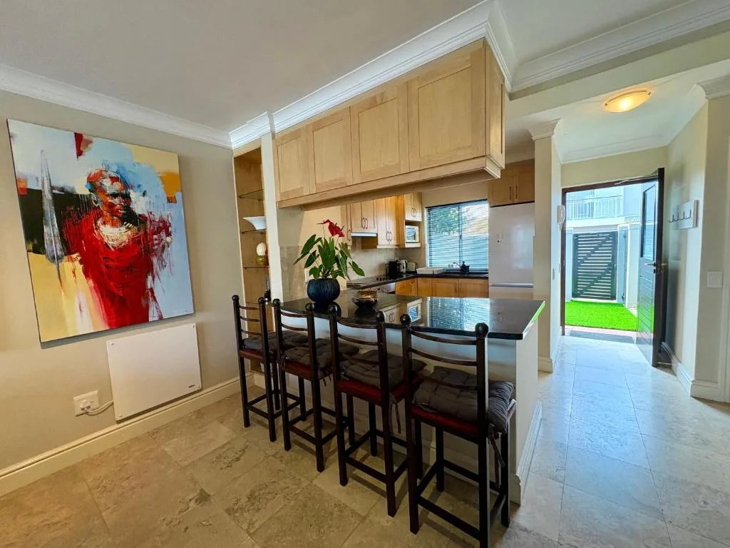 Open-plan dining area with black bar stools and kitchen view beyond