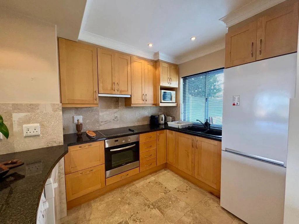 Spacious kitchen with wooden cabinetry, black countertops, and stainless steel appliances