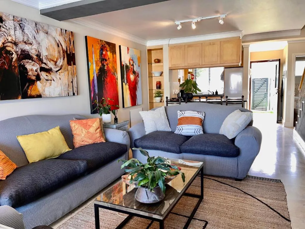 Modern living room with blue sofas, colorful artwork, and natural light