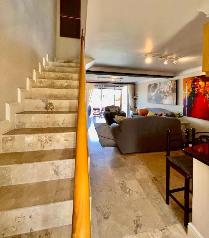Spacious open-plan lounge with dark sofa, artwork, and staircase entrance