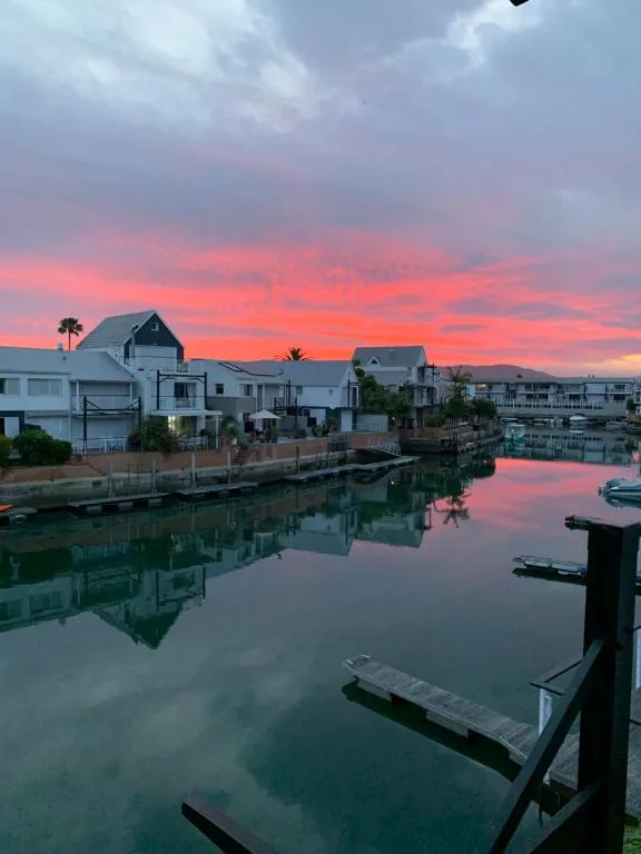 Stunning sunset over calm waterfront with moored boats and properties