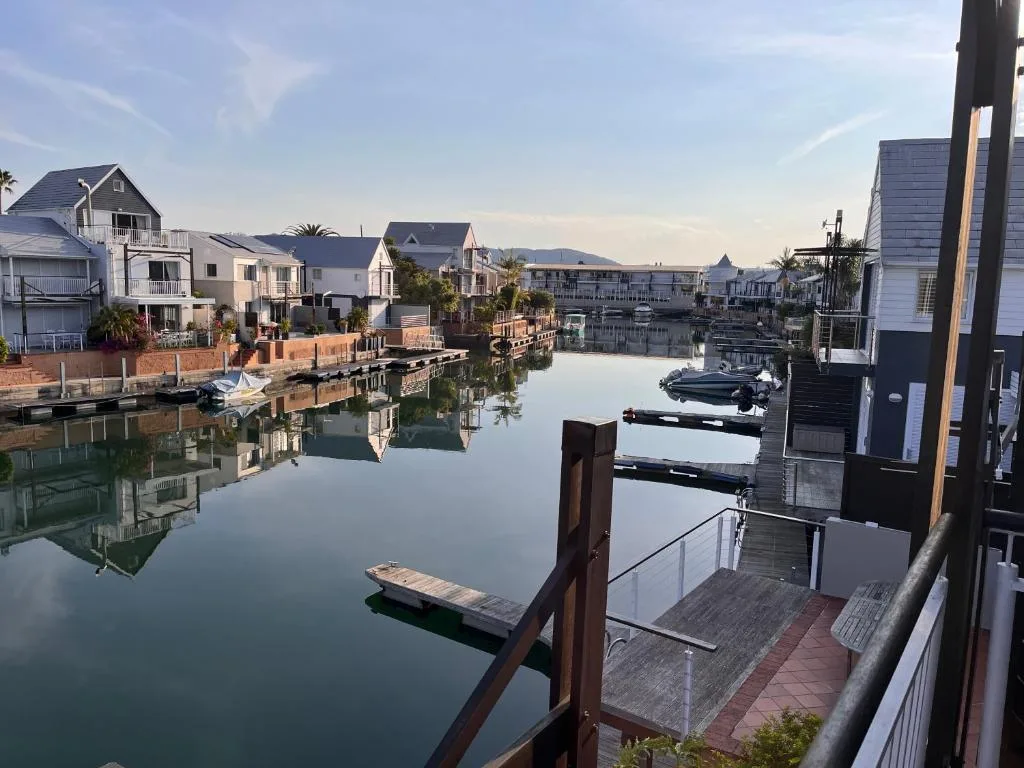 Waterfront canal view with moored boats and residential properties reflecting in still water