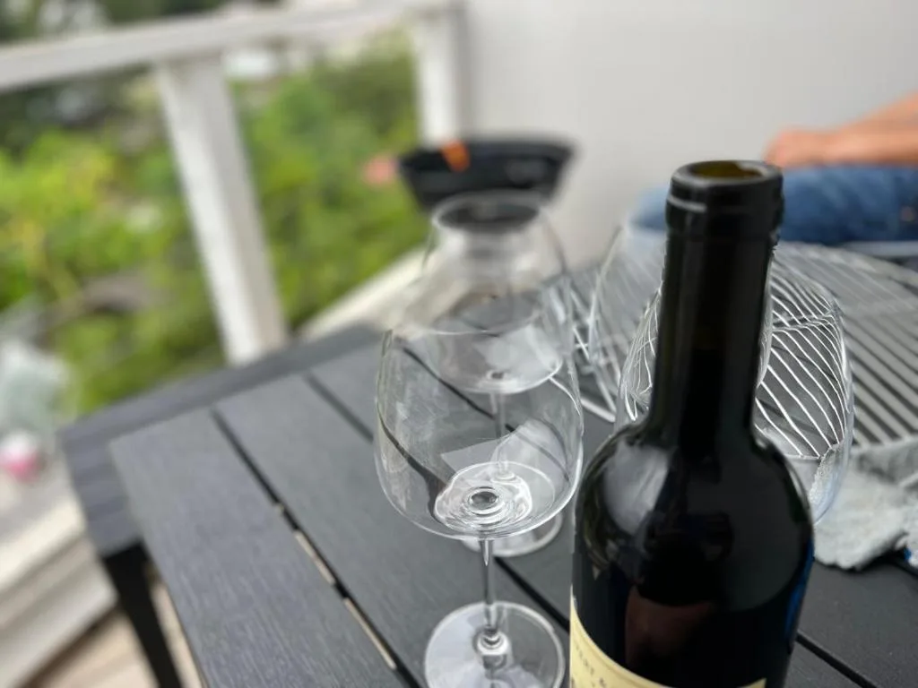 Wine bottle and glasses on outdoor table with garden view