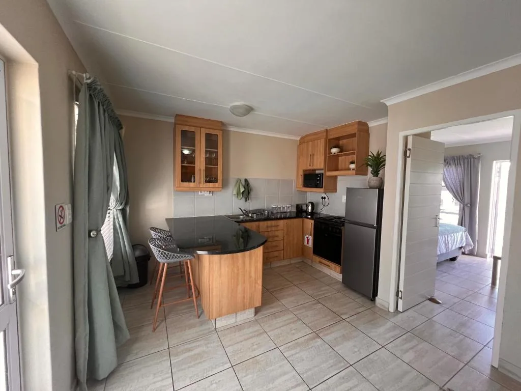 Modern kitchen with wooden cabinetry, black countertop, and island seating