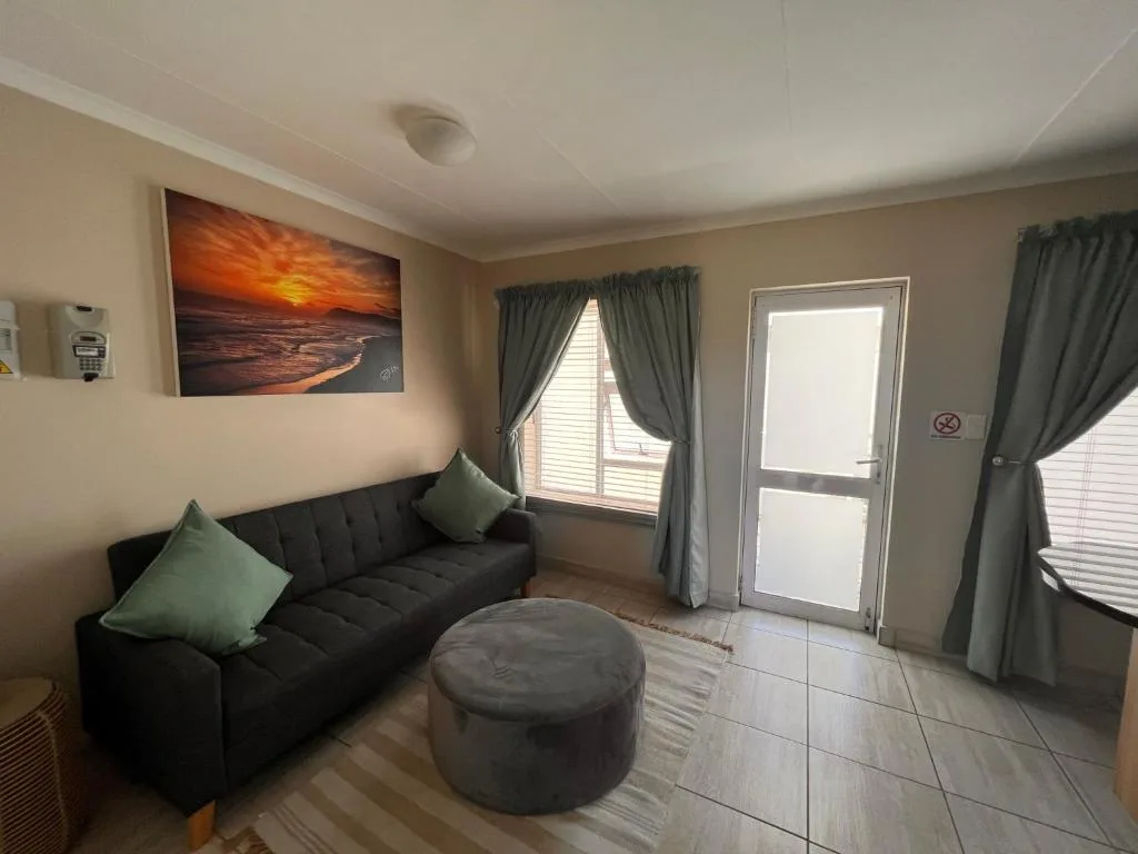 Living room with black sofa, gray ottoman, and sunset artwork