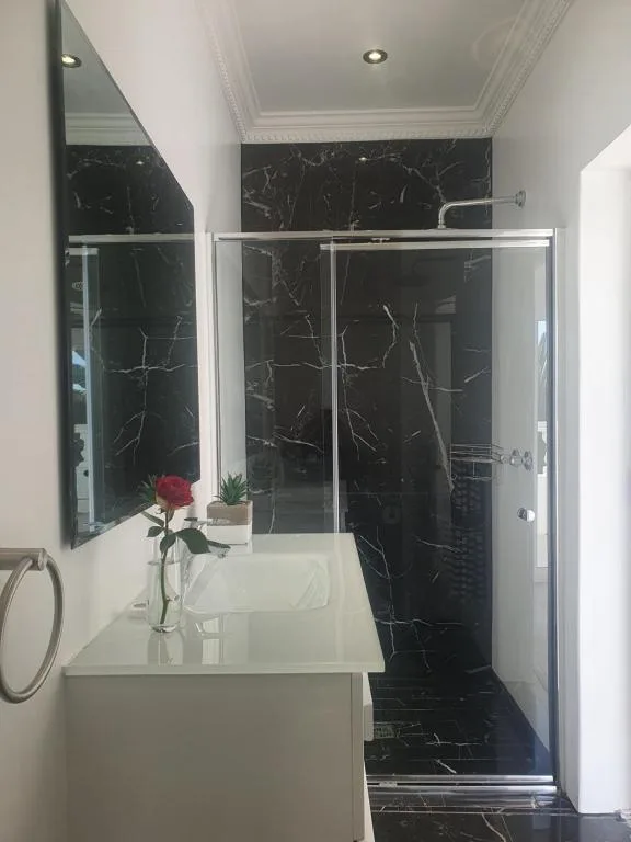 Modern bathroom with black marble shower enclosure and white vanity