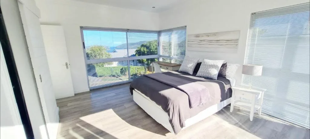 Bright bedroom with water views through corner windows and modern furnishings