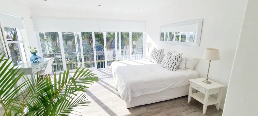 Bright bedroom with large sliding doors opening to a deck with garden views
