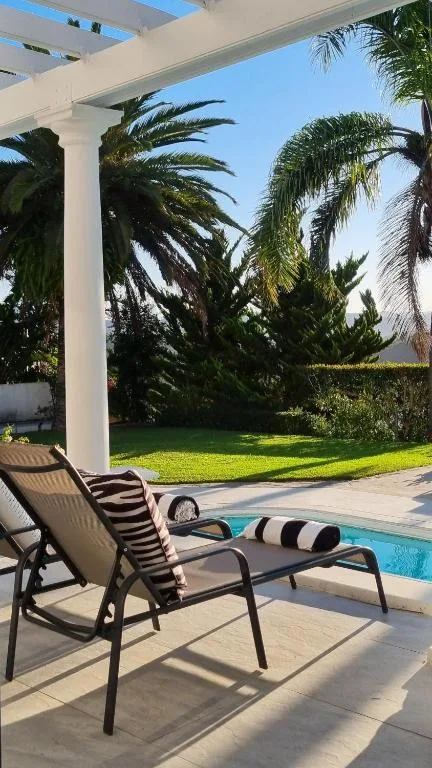 Lounge chairs on patio overlooking manicured garden and swimming pool