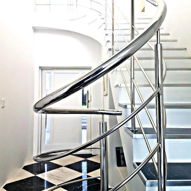 Modern spiral staircase with curved black handrail and metal railings