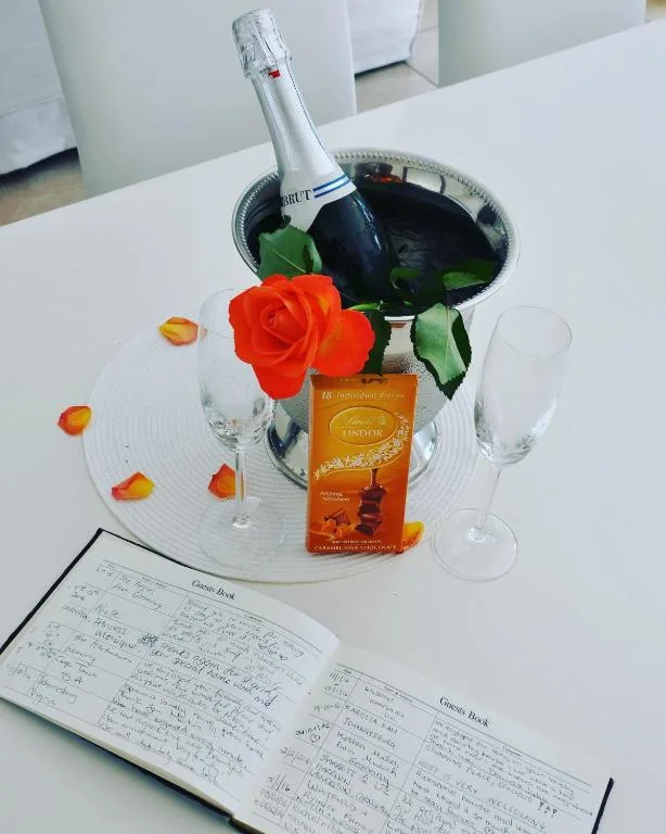 Champagne bottle with red rose and wine glasses on table