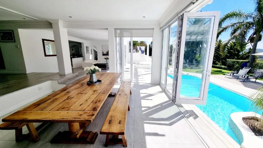 Wooden dining table with benches overlooking pool area through large windows