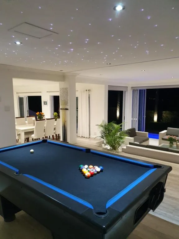 Modern lounge with pool table, starlit ceiling, and evening views