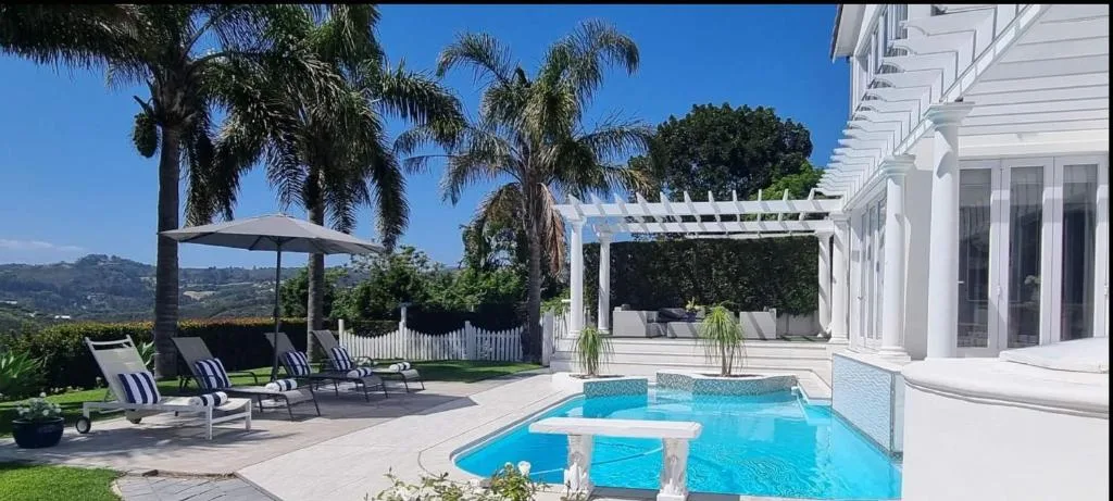Sparkling blue swimming pool with white pergola and mountain views