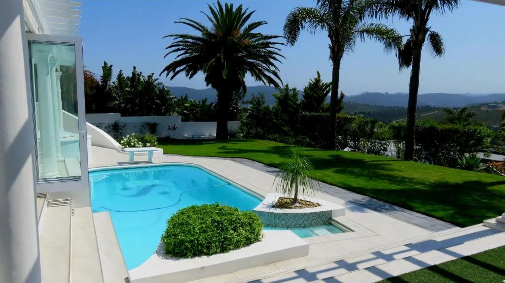 Sparkling blue swimming pool with manicured gardens and mountain views beyond