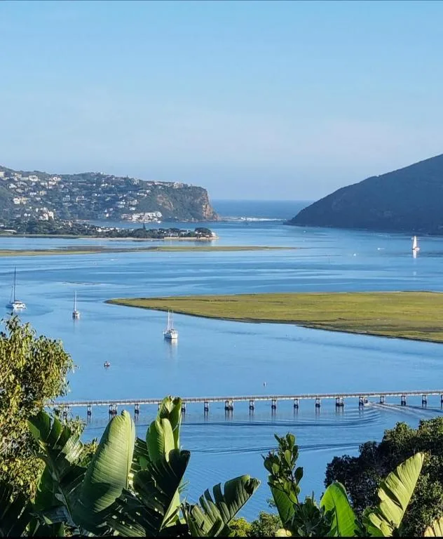 Scenic lagoon view with sailboats, green marsh, and coastal mountains