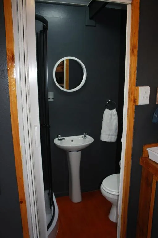 Modern bathroom with pedestal sink, round mirror, toilet, and shower cubicle