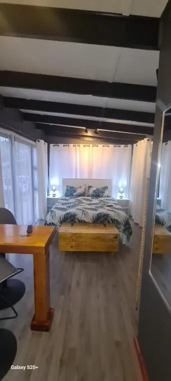 Modern bedroom with striped ceiling, bed with patterned duvet, and wooden furniture