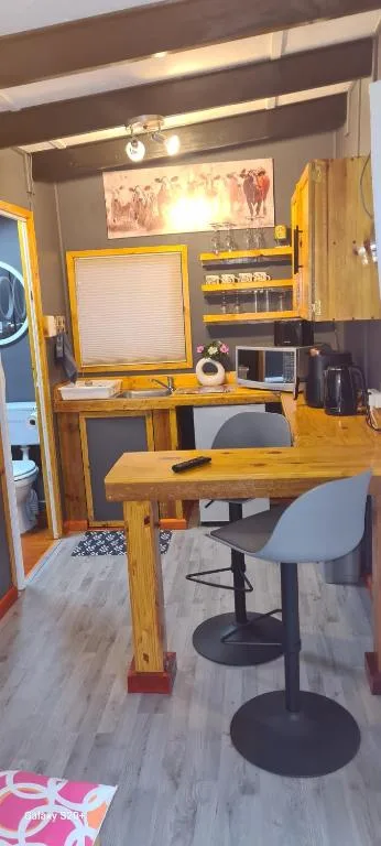 Wooden desk workspace with chairs and storage shelving in studio apartment