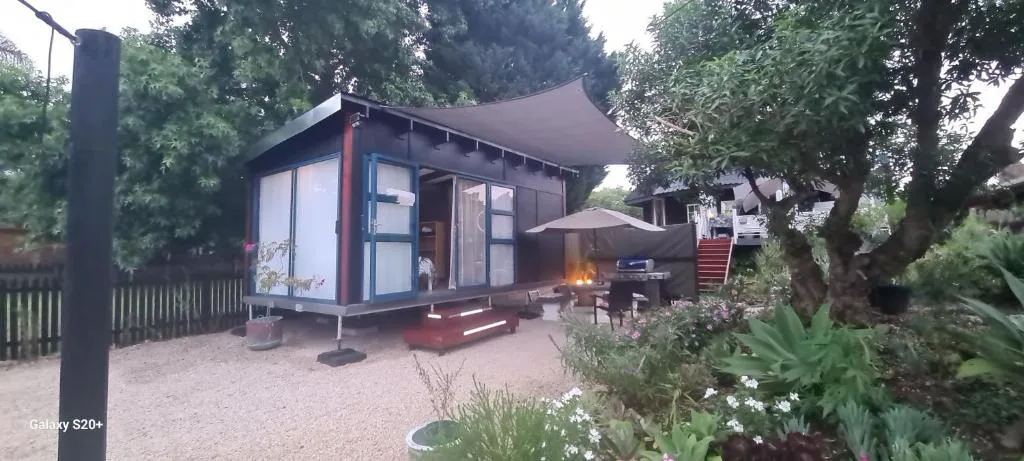 Modern studio cabin with black frame and white panels in garden setting