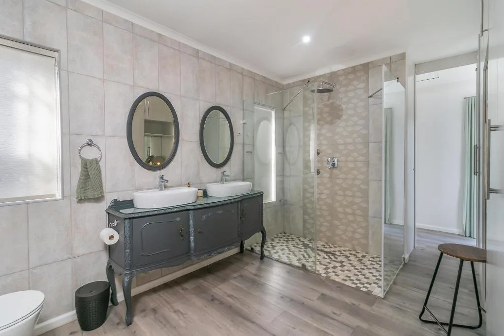 Modern bathroom with double vanity, large mirrors, and walk-in shower enclosure