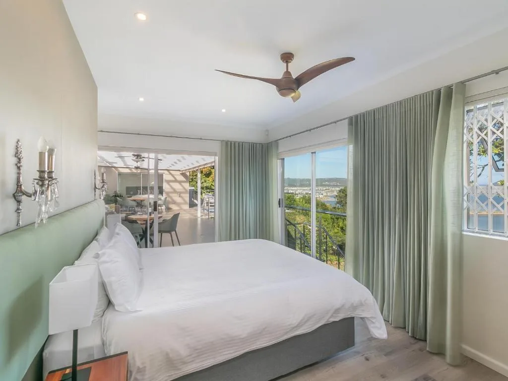 Bright bedroom with queen bed, ceiling fan, and panoramic views of Knysna