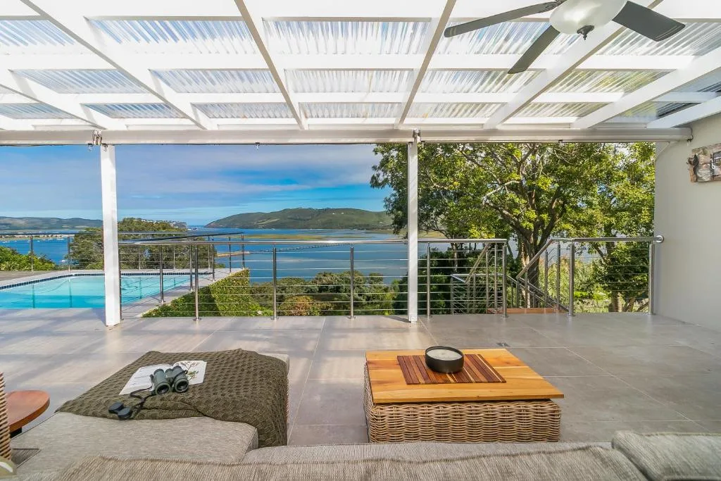 Covered deck with pool, seating, and scenic lagoon views beyond