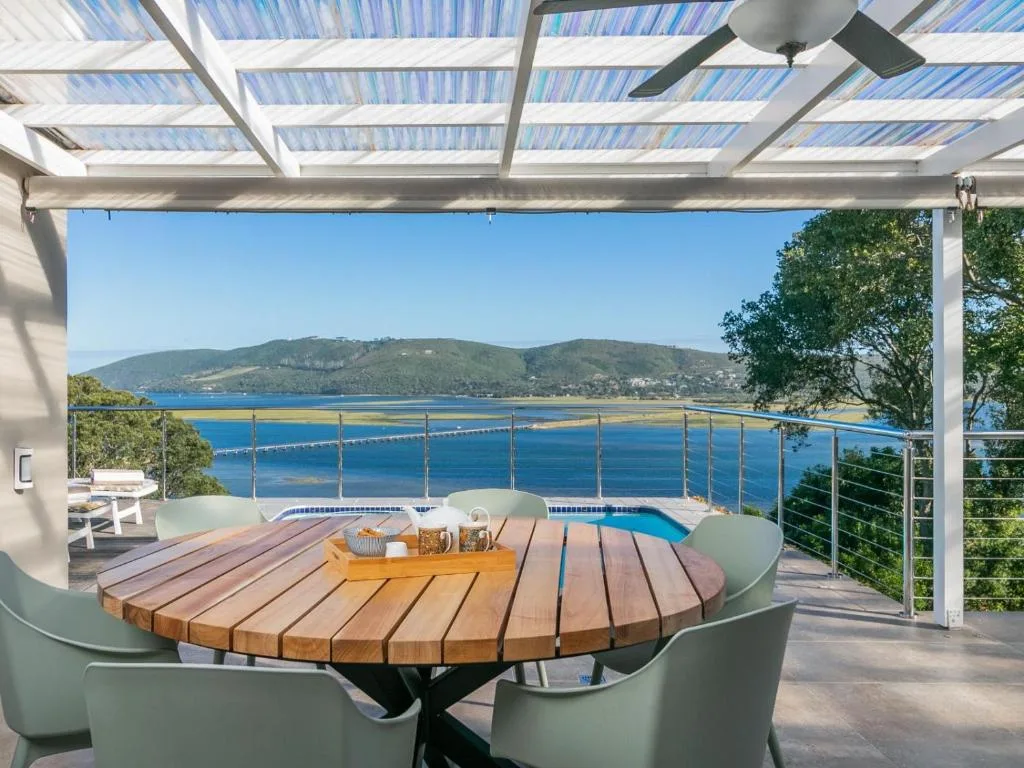 Covered deck with dining table overlooking Knysna lagoon and mountains