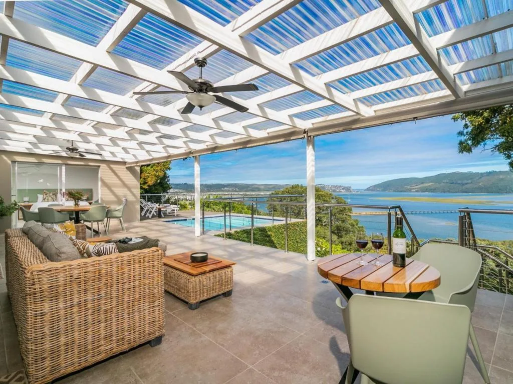 Covered patio with polycarbonate roof, wicker furniture, pool and lagoon views