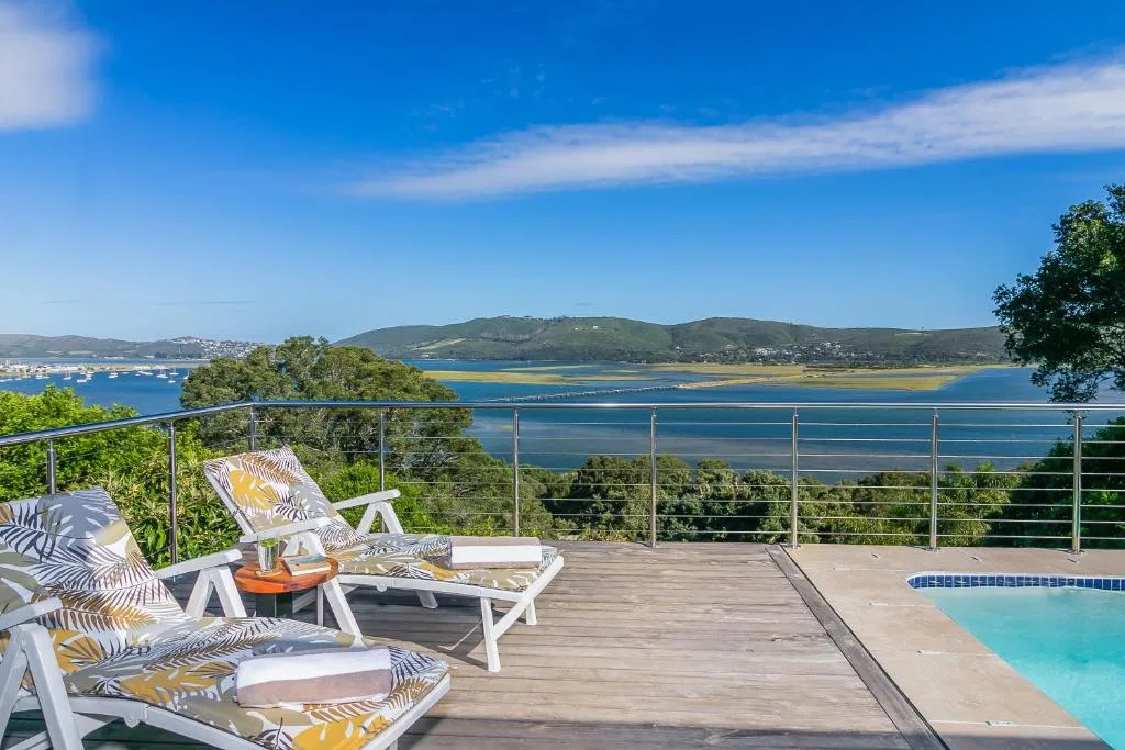 Wooden deck with loungers, pool, and panoramic lagoon views