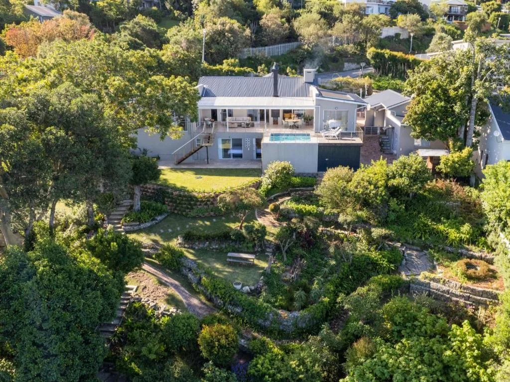 Aerial view of modern villa with pool surrounded by lush gardens and trees