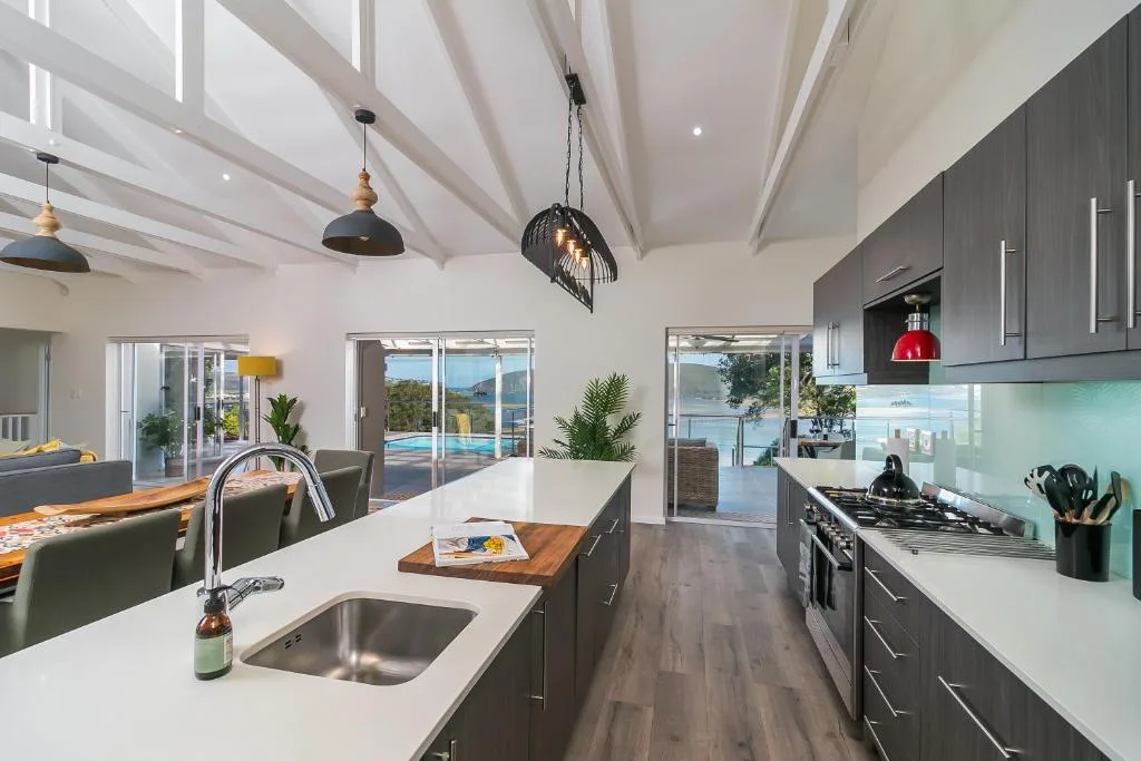 Modern open-plan kitchen with dark cabinetry, island sink, and pendant lighting