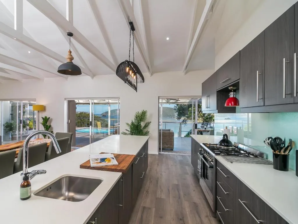 Modern kitchen with dark cabinetry, gas stove, and mountain views through glass doors
