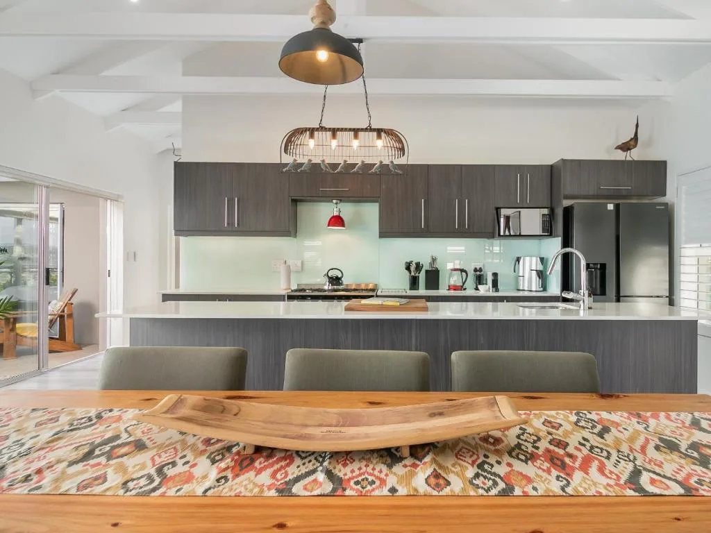 Modern kitchen with dark cabinetry, white countertops, and pendant lighting overhead