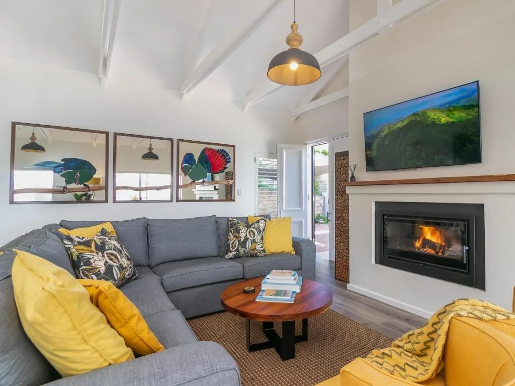 Modern lounge with gray sofa, yellow accents, fireplace, and bird artwork
