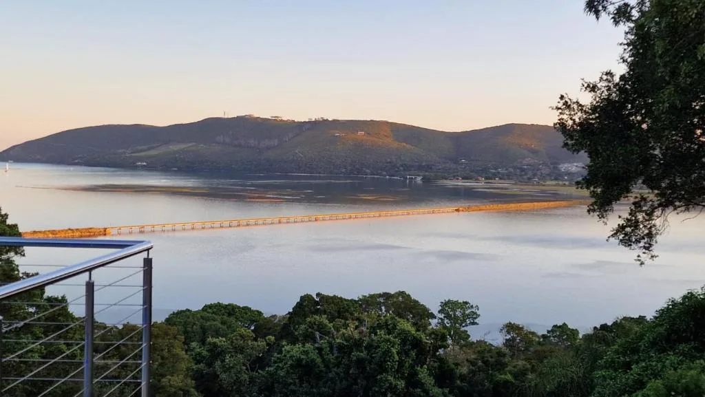 Expansive Knysna Lagoon vista with mountains and bridge at sunrise