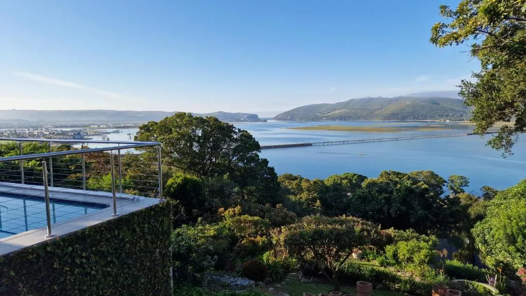 Panoramic lagoon and mountain vista from modern deck with pool railing