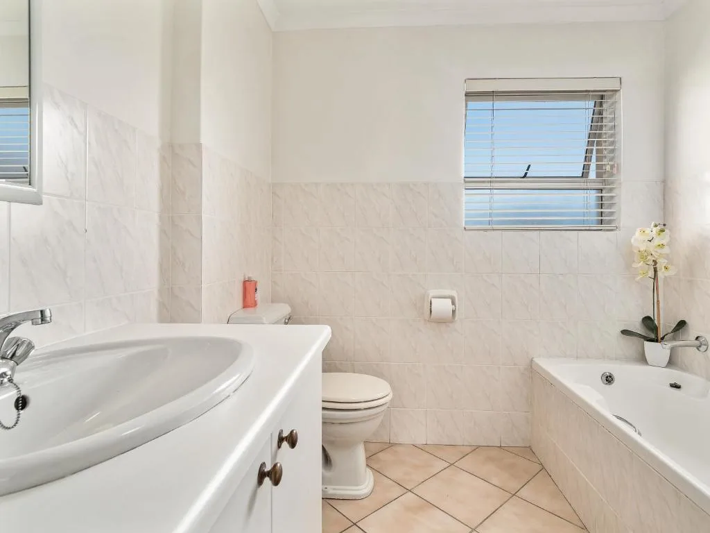 Bright bathroom with sink, toilet, bathtub, and ocean view window
