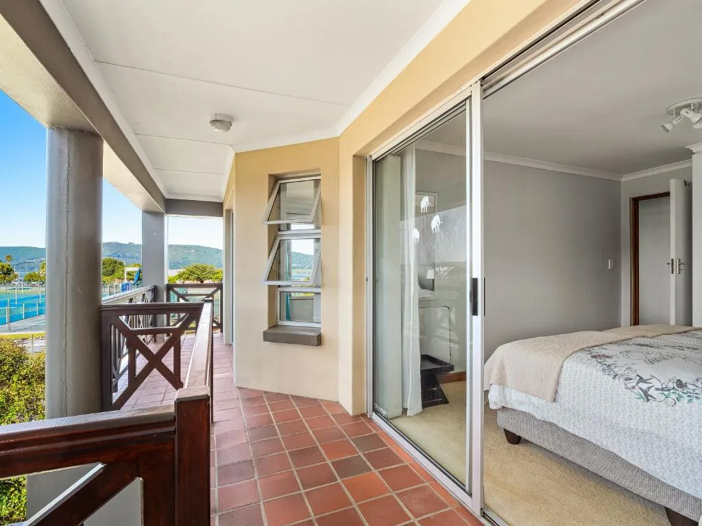 Spacious bedroom with bed, sliding glass doors opening to ocean view balcony