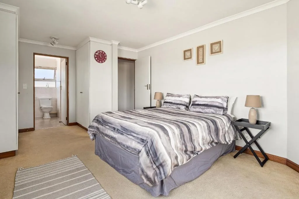 Spacious bedroom with striped bedding, ensuite bathroom, and wall art