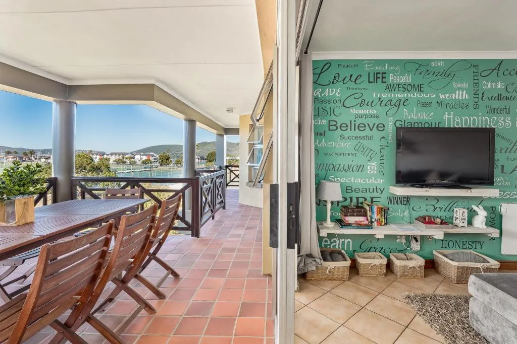 Covered deck with dining table overlooking lagoon and mountains in Knysna
